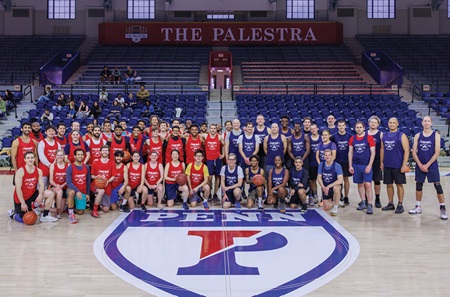 Teams in red and blue jerseys pose on center court at the Palestra.